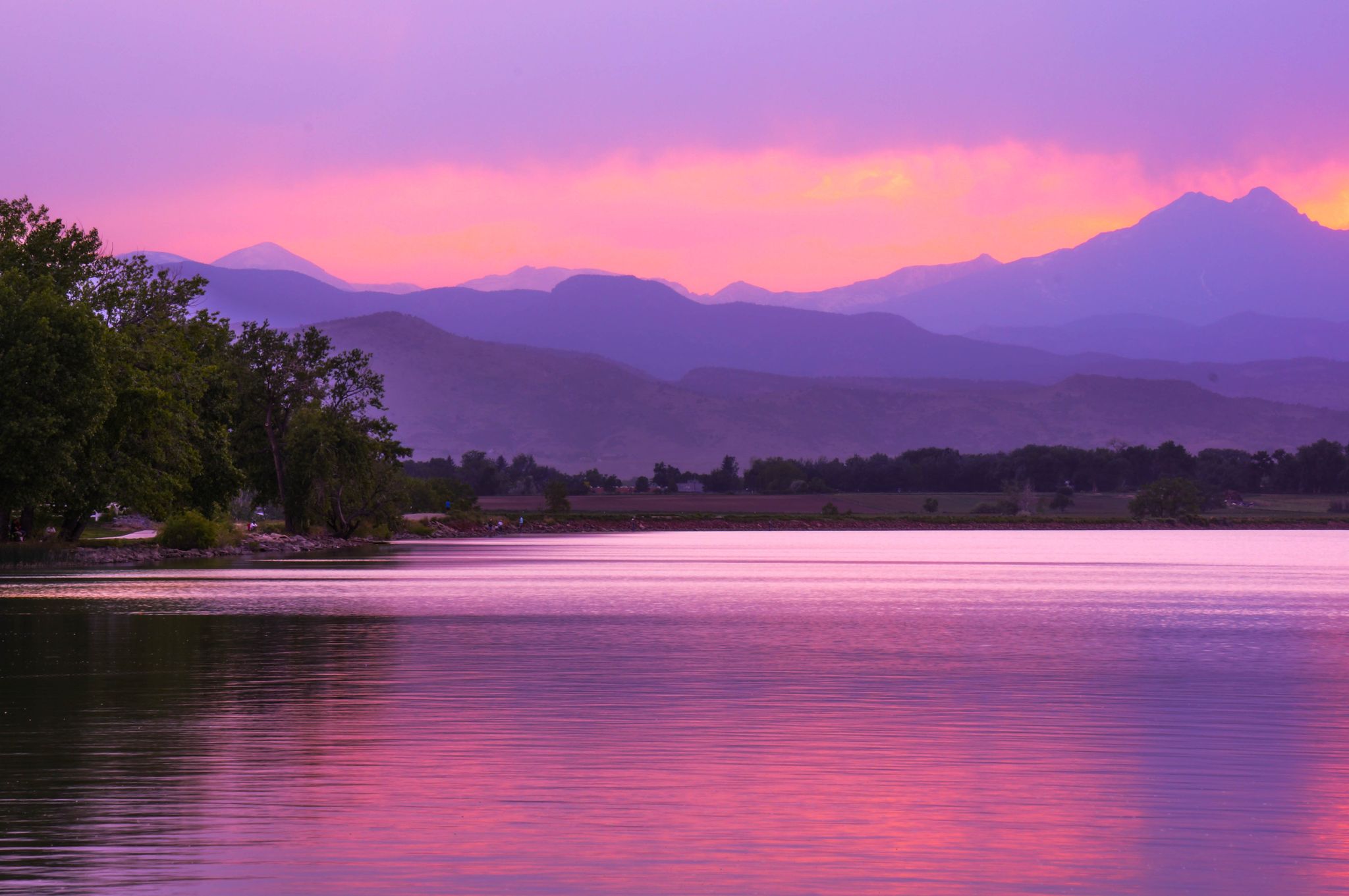 Vibrant purple and pink sunset over a calm lake with distant mountains. - McIntosh Lake loop