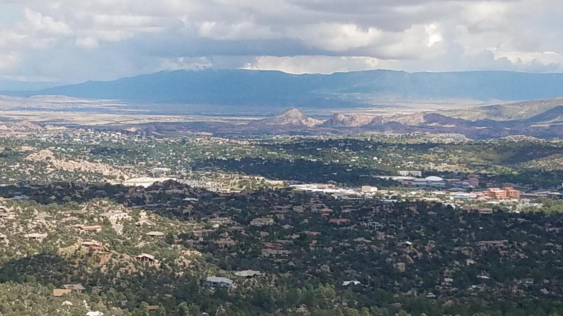 Overlook of a sprawling town in a valley with mountains under cloudy skies.