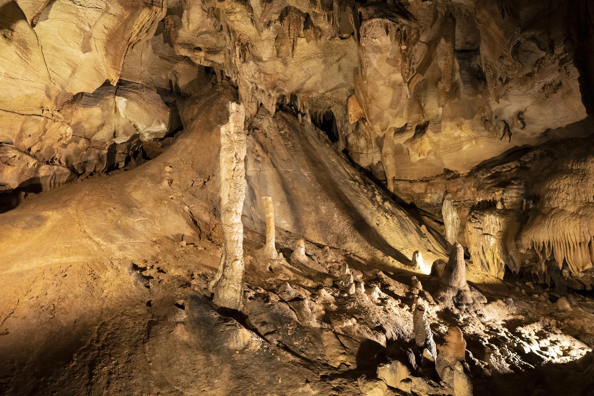 A dimly lit cave interior reveals impressive stalagmites and rock formations.