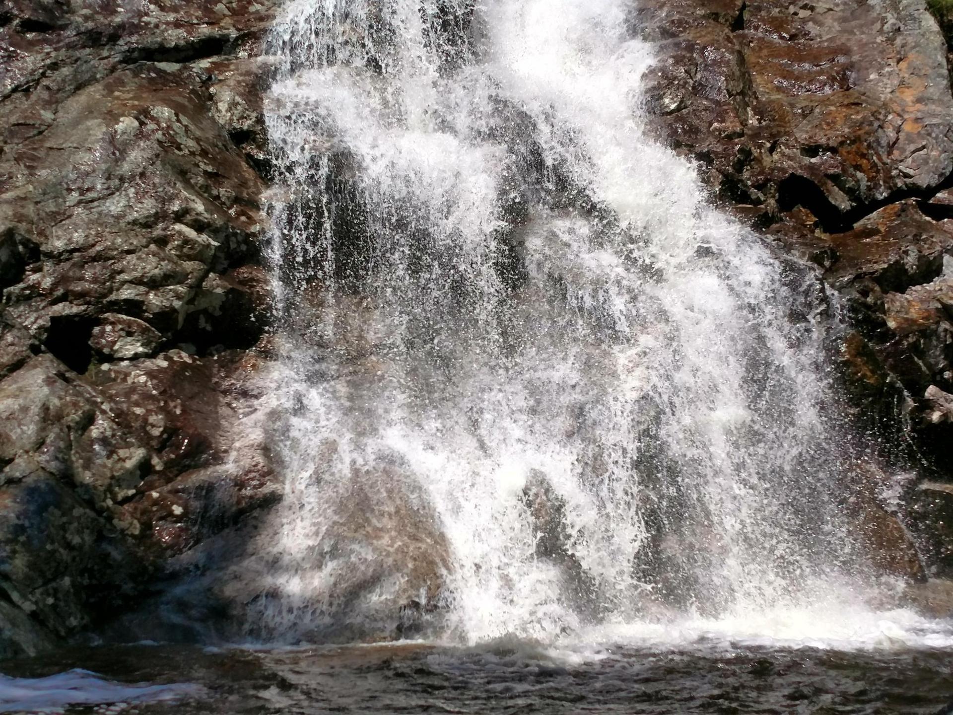 Close-up of a powerful waterfall cascading over dark rocks.