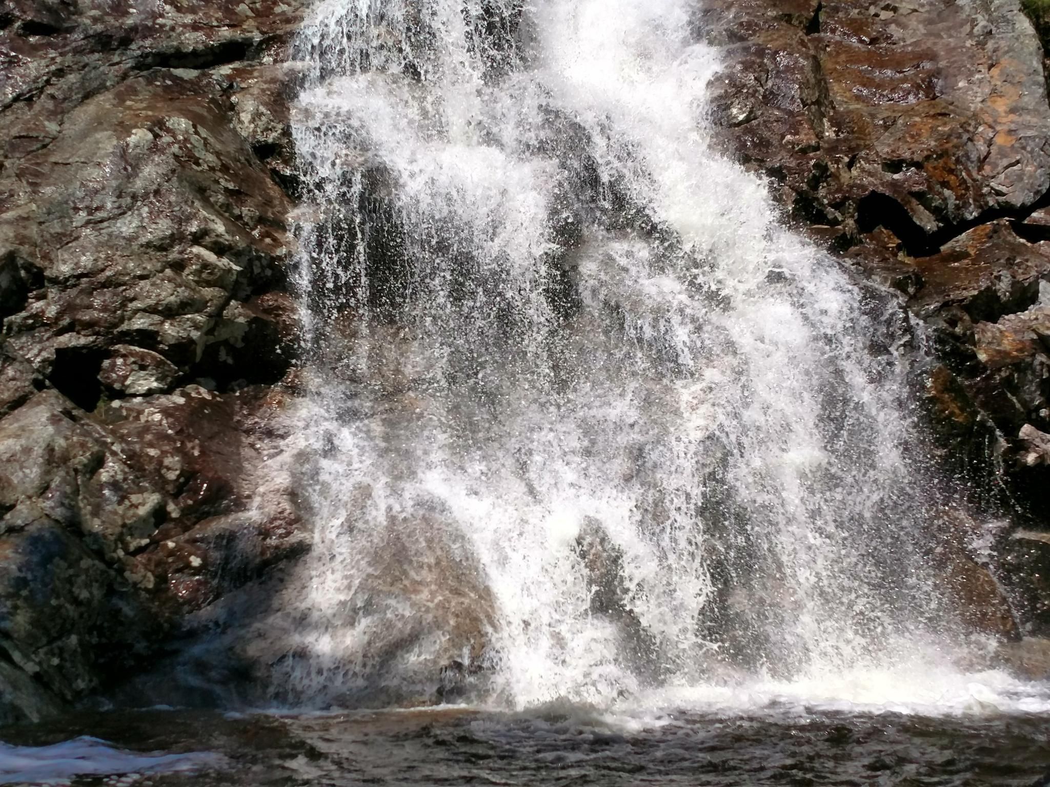 Close-up of a powerful waterfall cascading over dark rocks. - Nancy Cascades