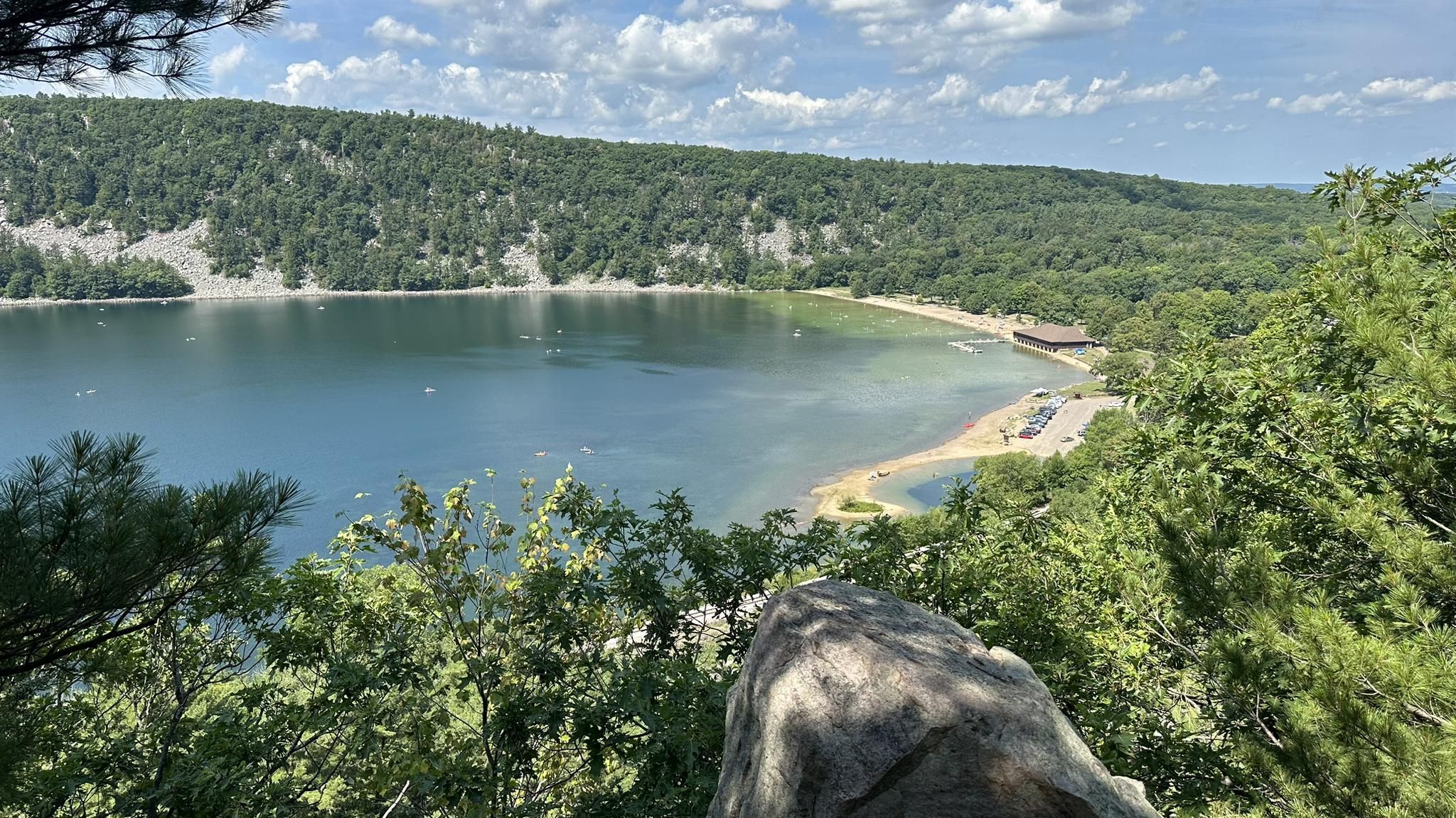 Overlook of a calm lake, sandy beach, and lush green forested hills. - Elephant Rock & Upland Trail Loop
