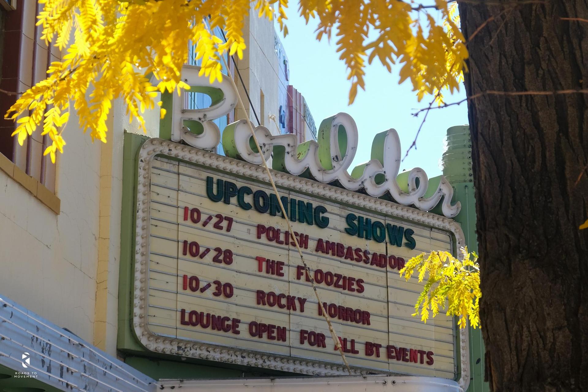 Vintage marquee sign advertising shows, framed by bright yellow autumn leaves.
