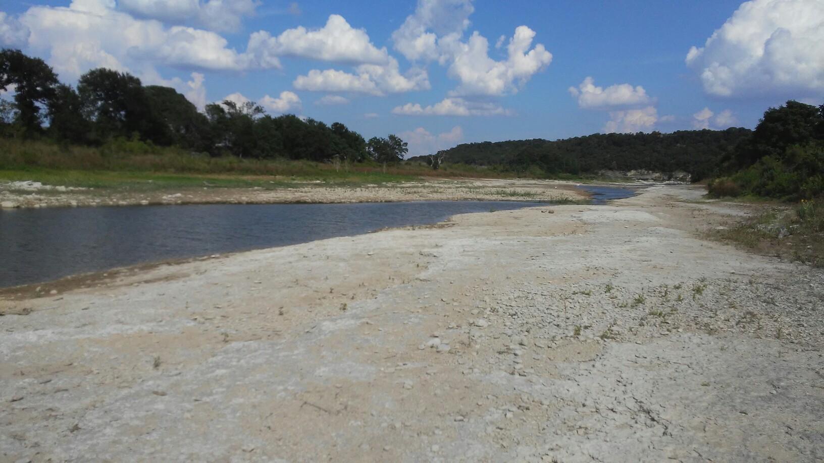 Wide river next to a large, dry, sandy bank under a cloudy sky.