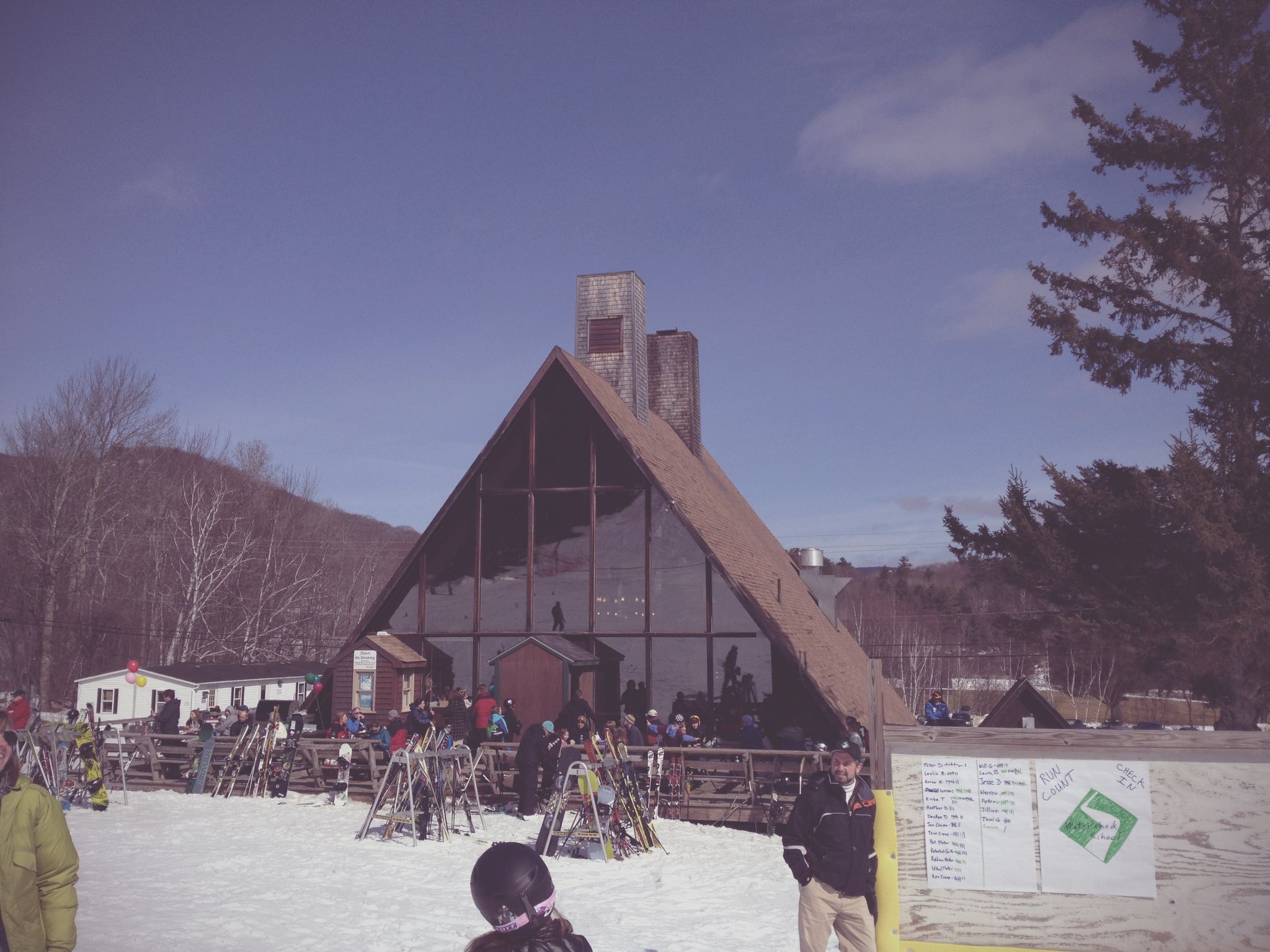 People gather outside a large A-frame lodge on a sunny, snowy day. - Camden Snowbowl – Camden Snowbowl Trailhead loop from Ragged Mountain Preserve
