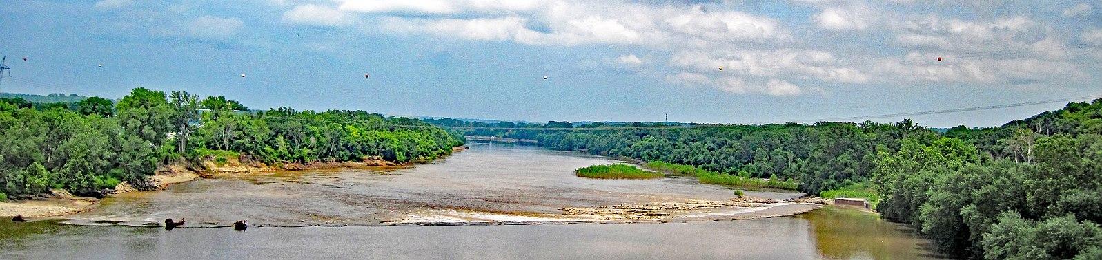 Panoramic view of a wide river winding through dense green forest.