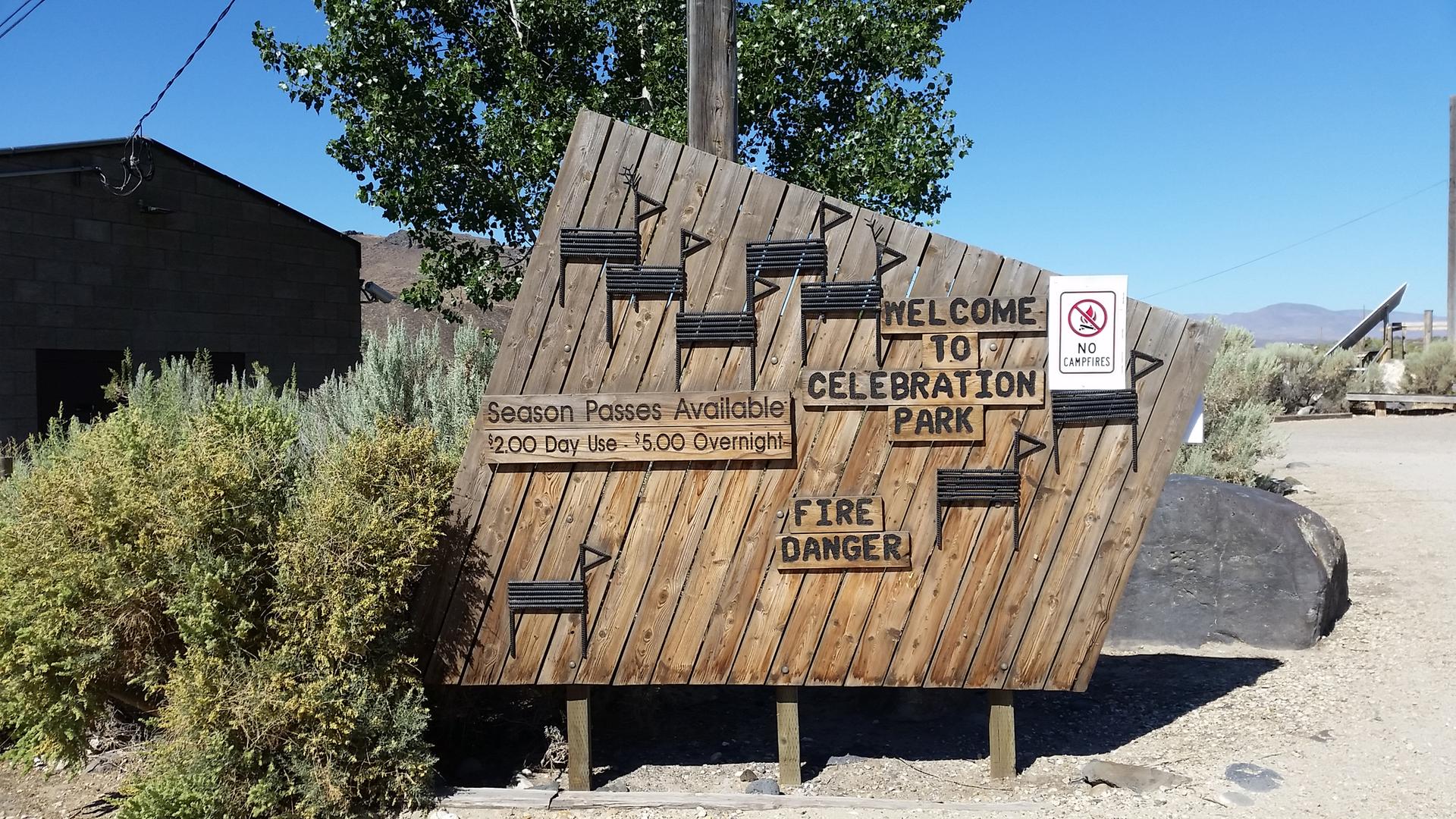 Large wooden sign with text and warnings under a bright sky.