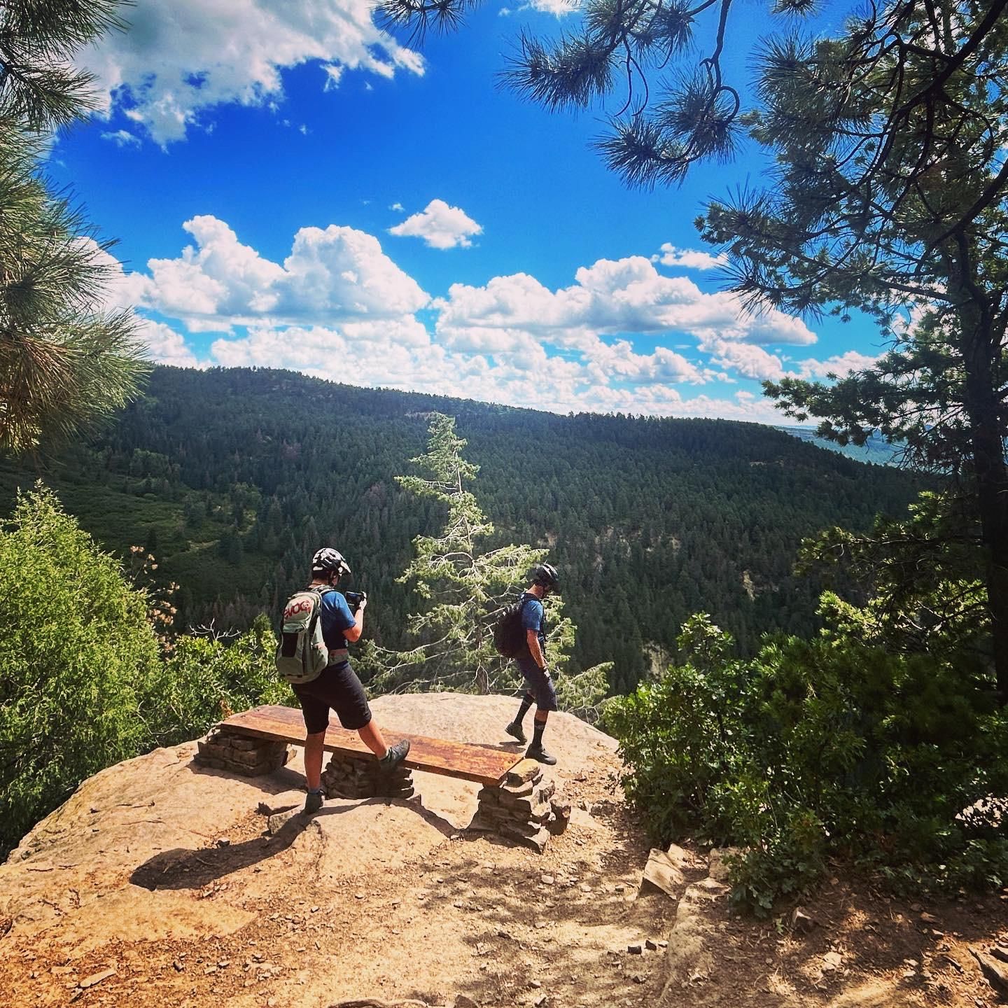 Two hikers with backpacks stand on a rocky overlook, admiring a vast forest. - Colorado Trail to Gudy's Rest