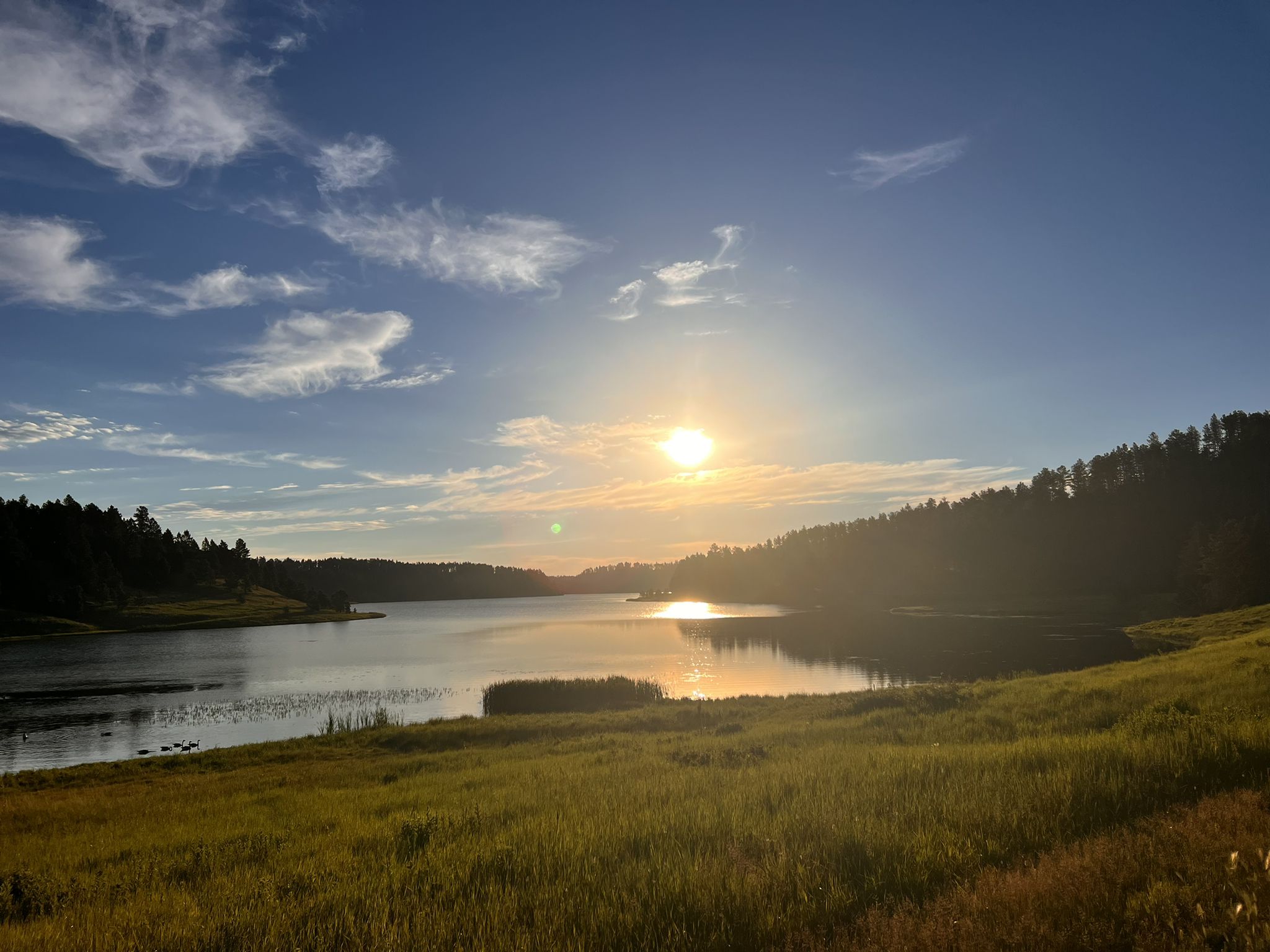 Golden sunset over a calm lake surrounded by dark forested hills. - Deerfield Lake Loop Trail #40L