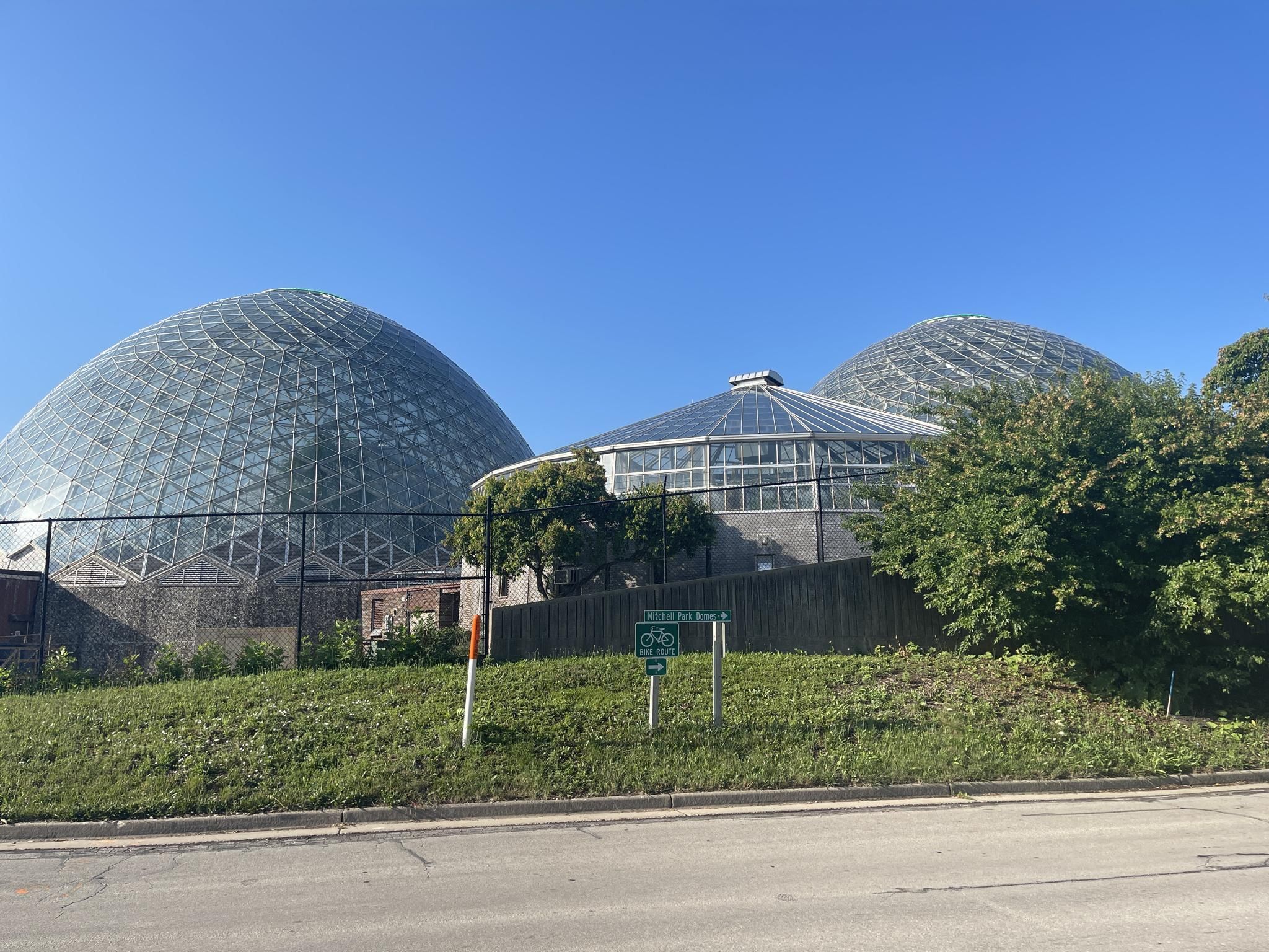 Three large glass domes on a grassy hill under a clear blue sky. - Hank Aaron State Trail