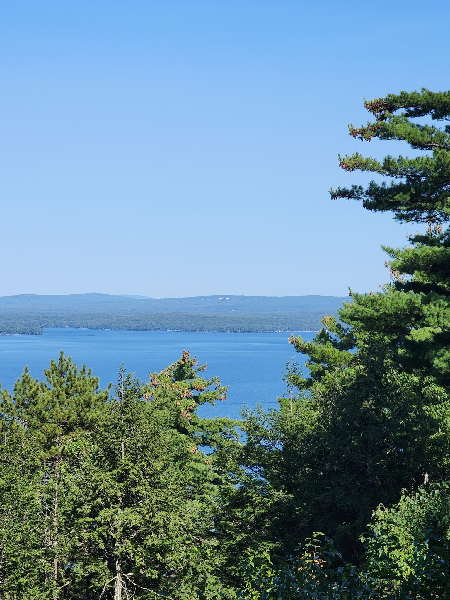 Wide view of a blue lake and distant mountains under clear sky.