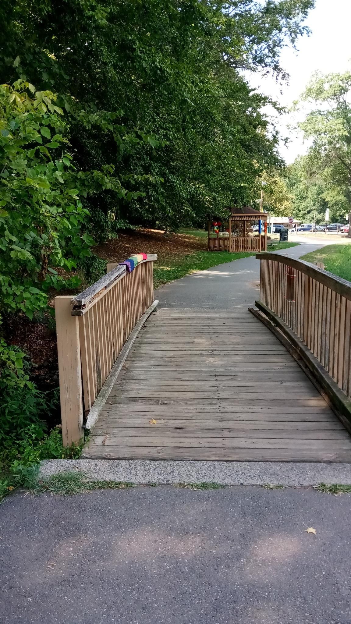 A wooden footbridge over a paved path, surrounded by green trees and a gazebo. - Nomahegan Park – Nomahegan Park Wooden Bridge loop from Union County