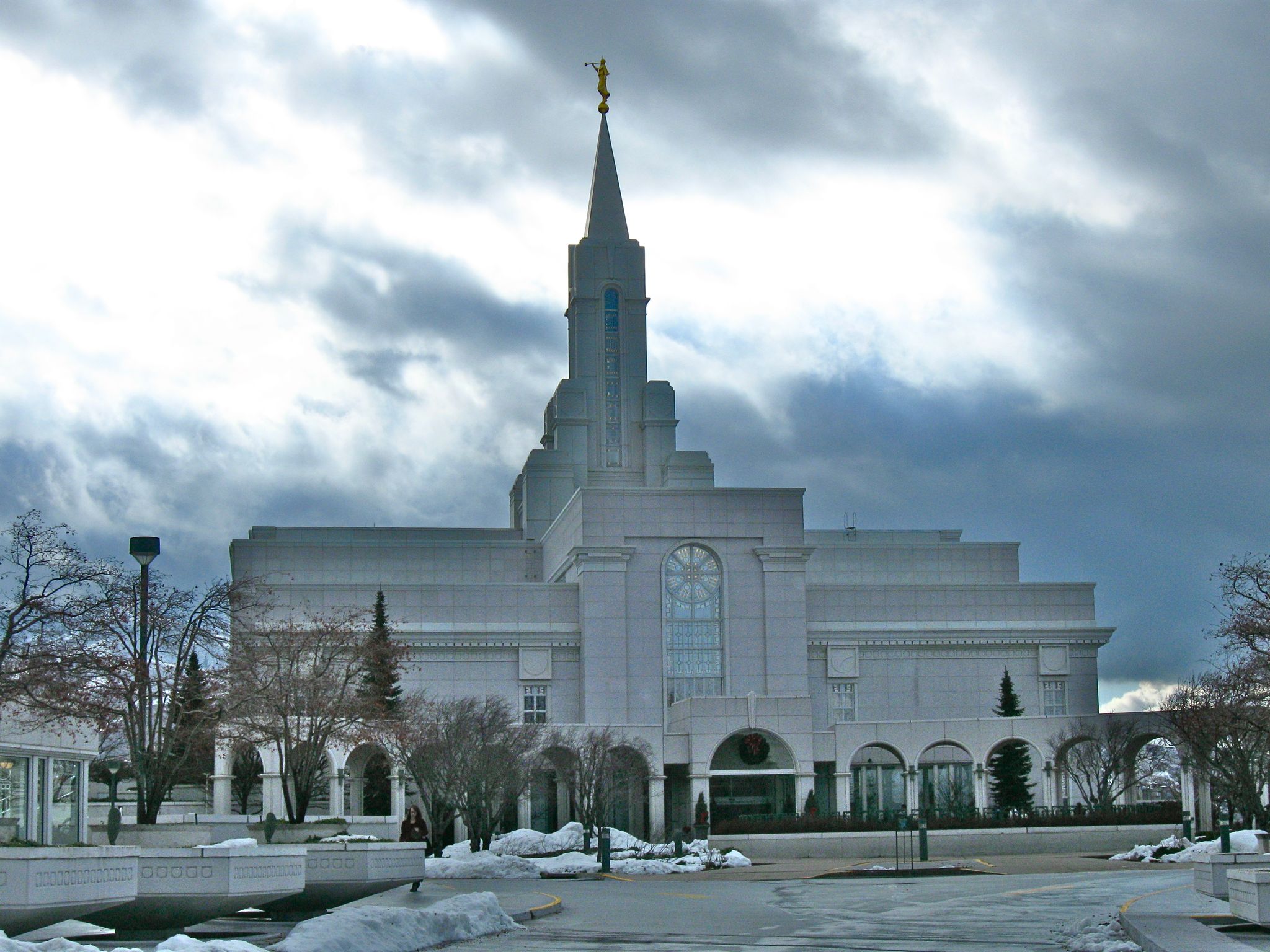White building with a spire and golden statue, surrounded by snow under cloudy sky. - Bountiful Utah Temple loop