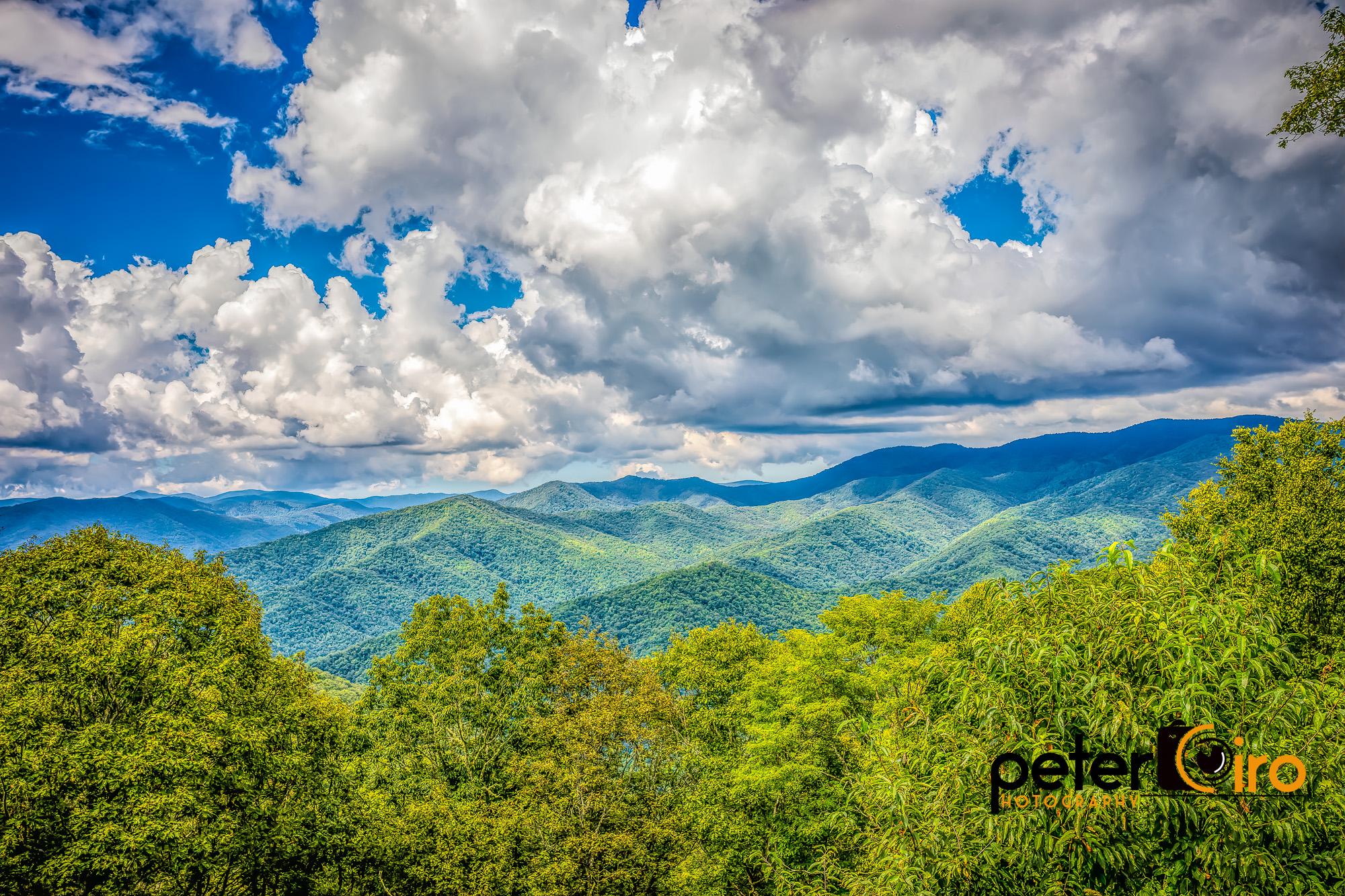Expansive green mountain range under a dramatic blue and white sky.