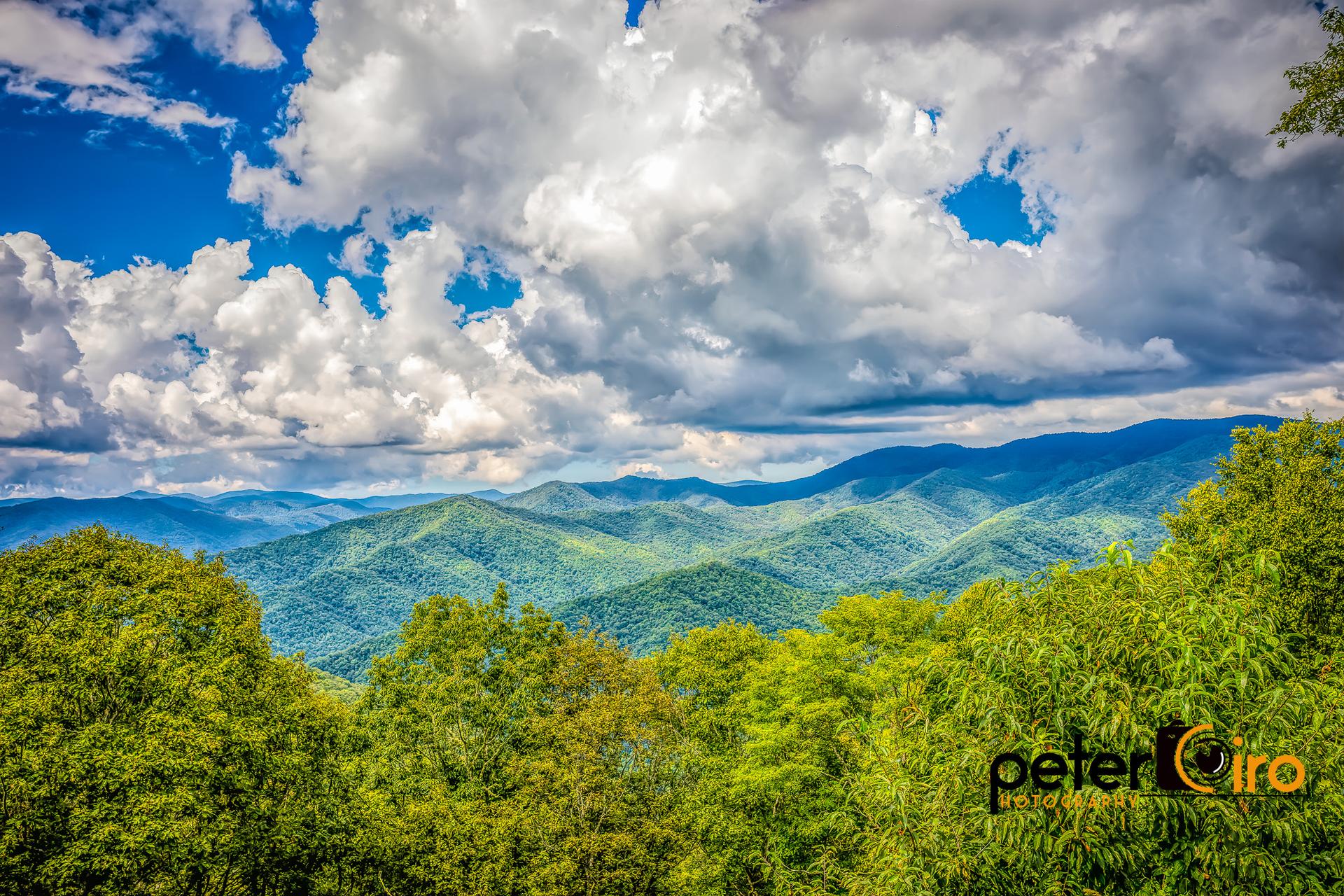 Expansive green mountain range under a dramatic blue and white sky.