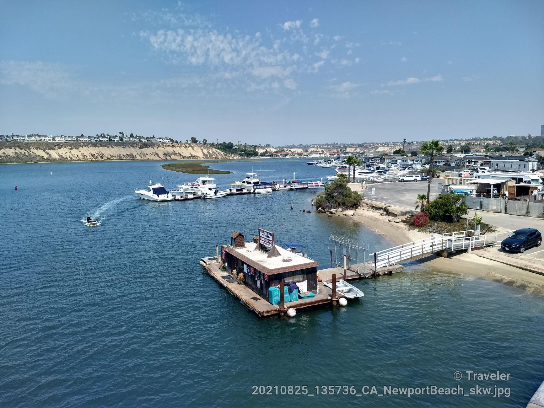 Sunny view of a houseboat and boats on calm water with a distant jet ski.
