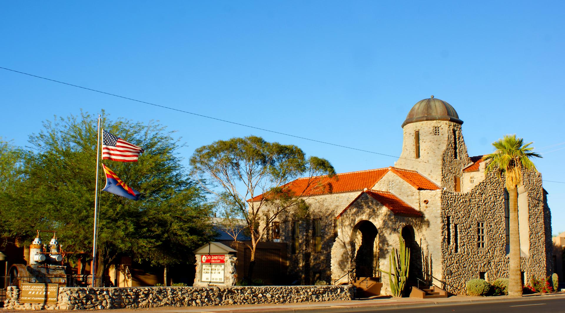 Stone building with a dome and red roof under clear blue sky.
