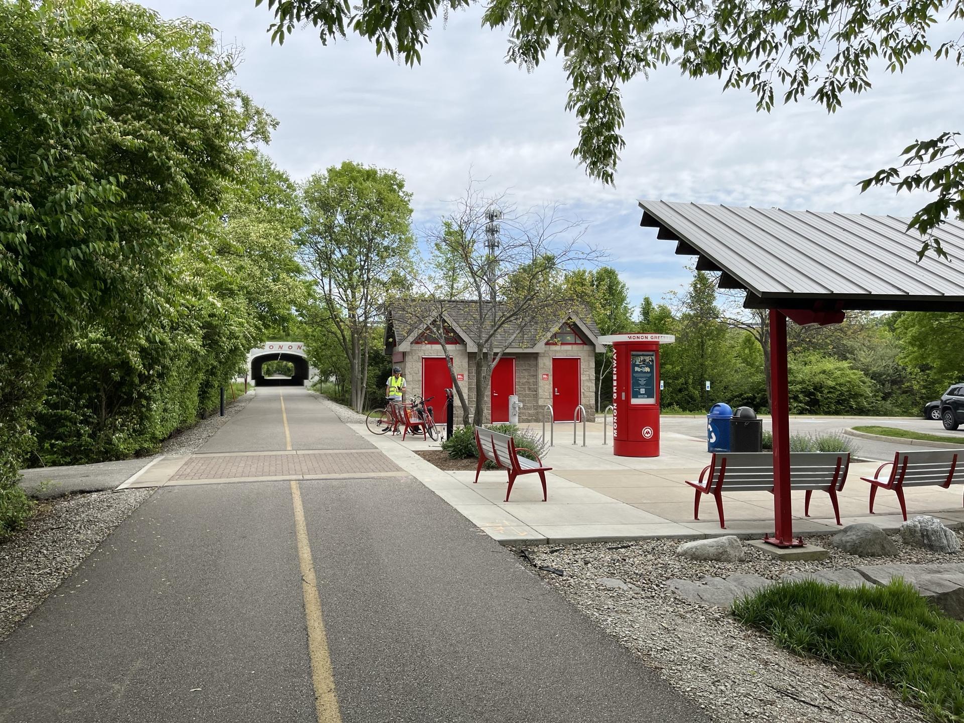 Paved trail leading to a small building and shelter, a person biking.