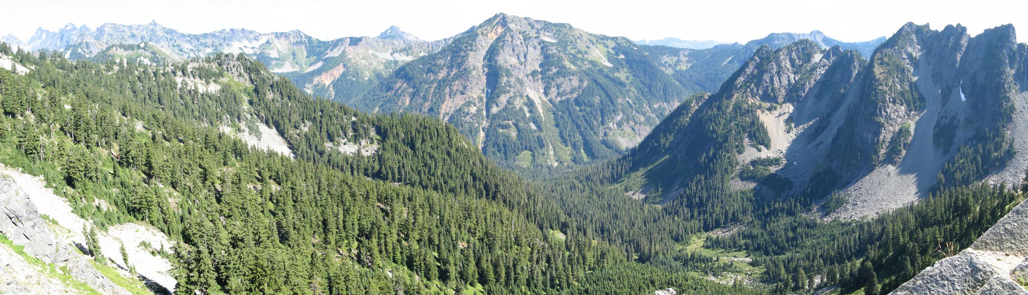 Panoramic view of a vast, green mountain range under bright daylight. - Kendall Peak Lakes Trail