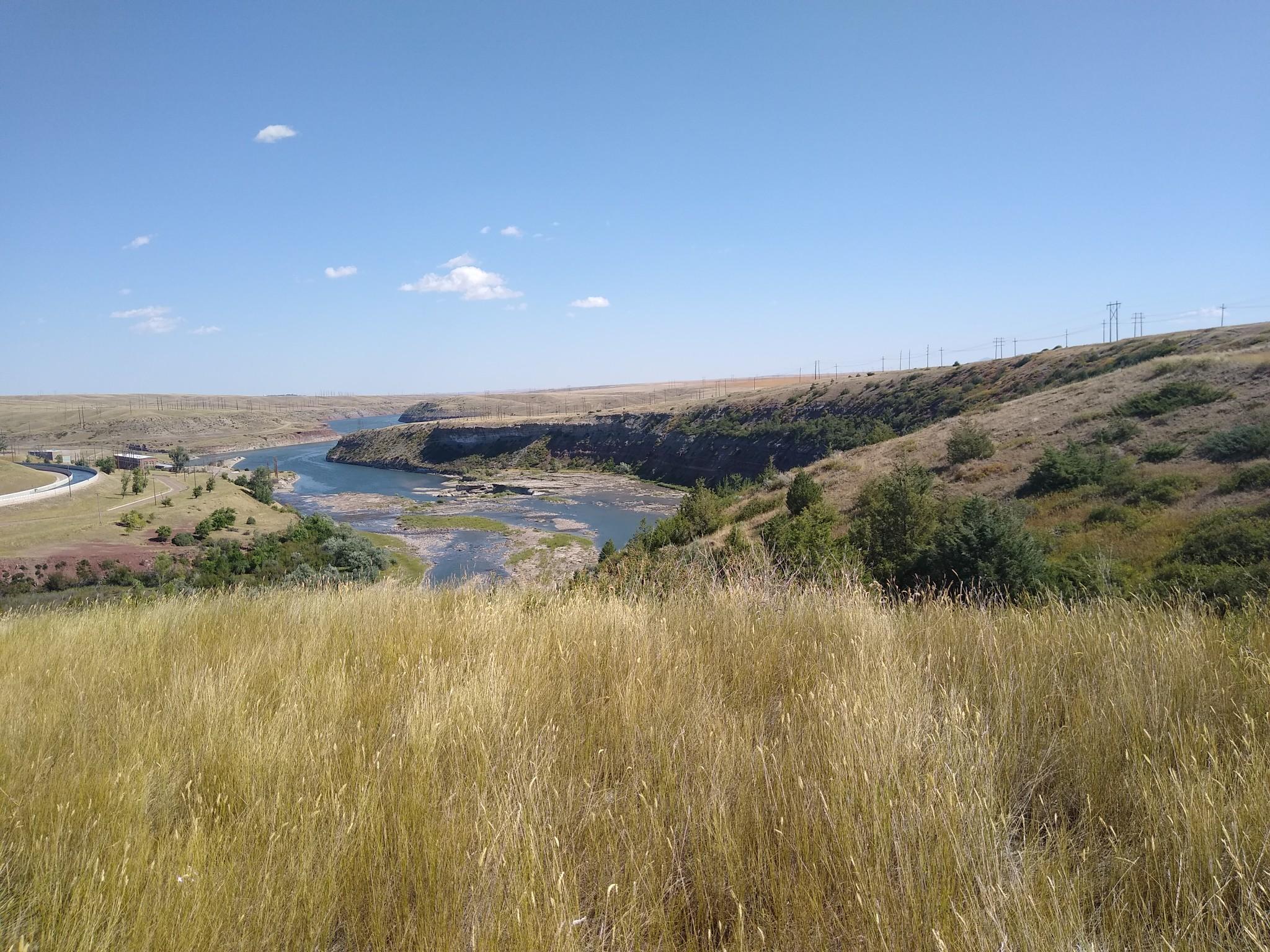 Sunny panoramic view of a wide river valley with dry golden grass.