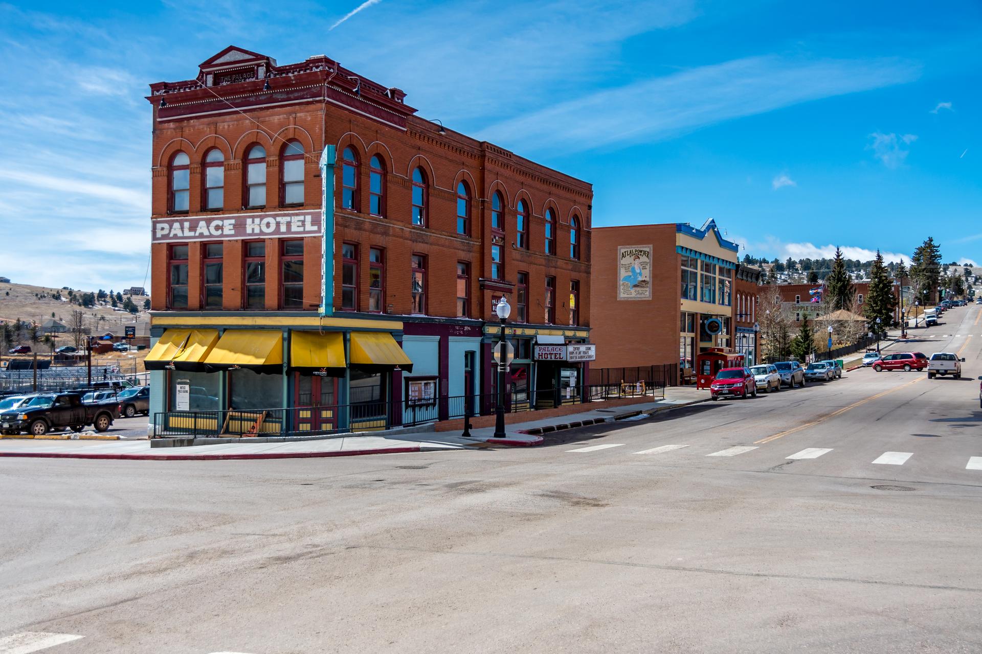 A historic brick building with a yellow awning stands on a sunny town street.
