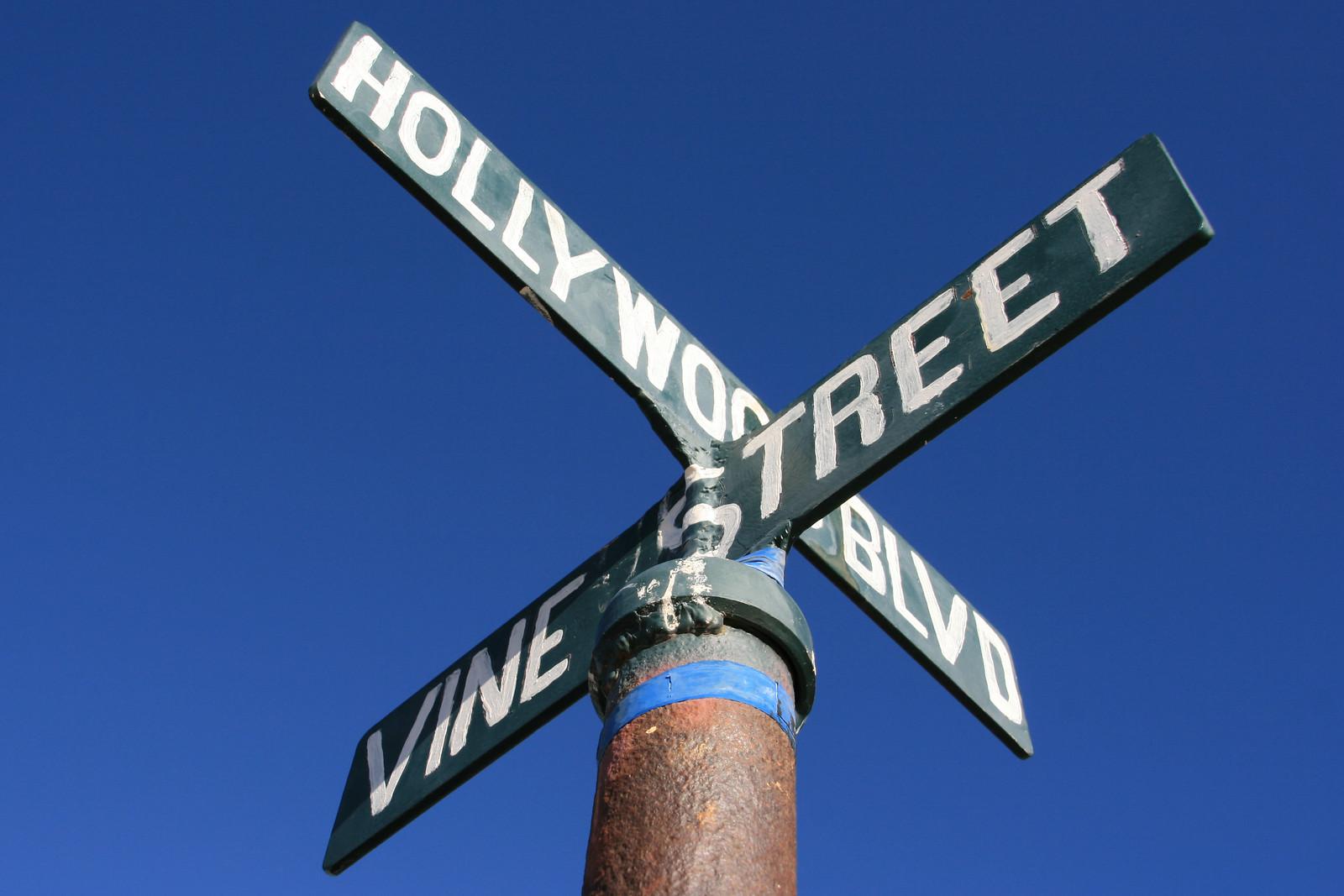 Four green street signs on a pole against a clear blue sky.