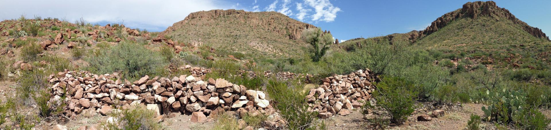 Panoramic view of desert mountains with low rock walls, bright day.