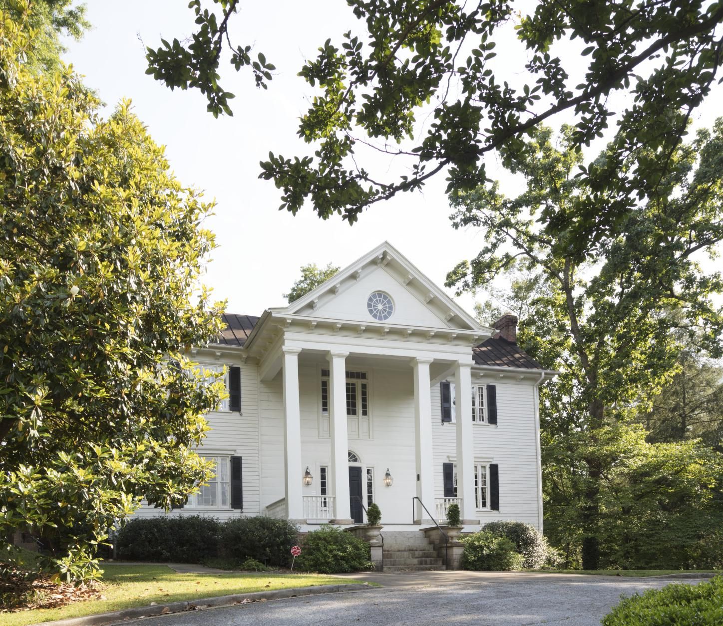 A grand white colonial house with large columns surrounded by green trees. - Swamp Rabbit Cafe & Grocery to Downtown Greenville loop