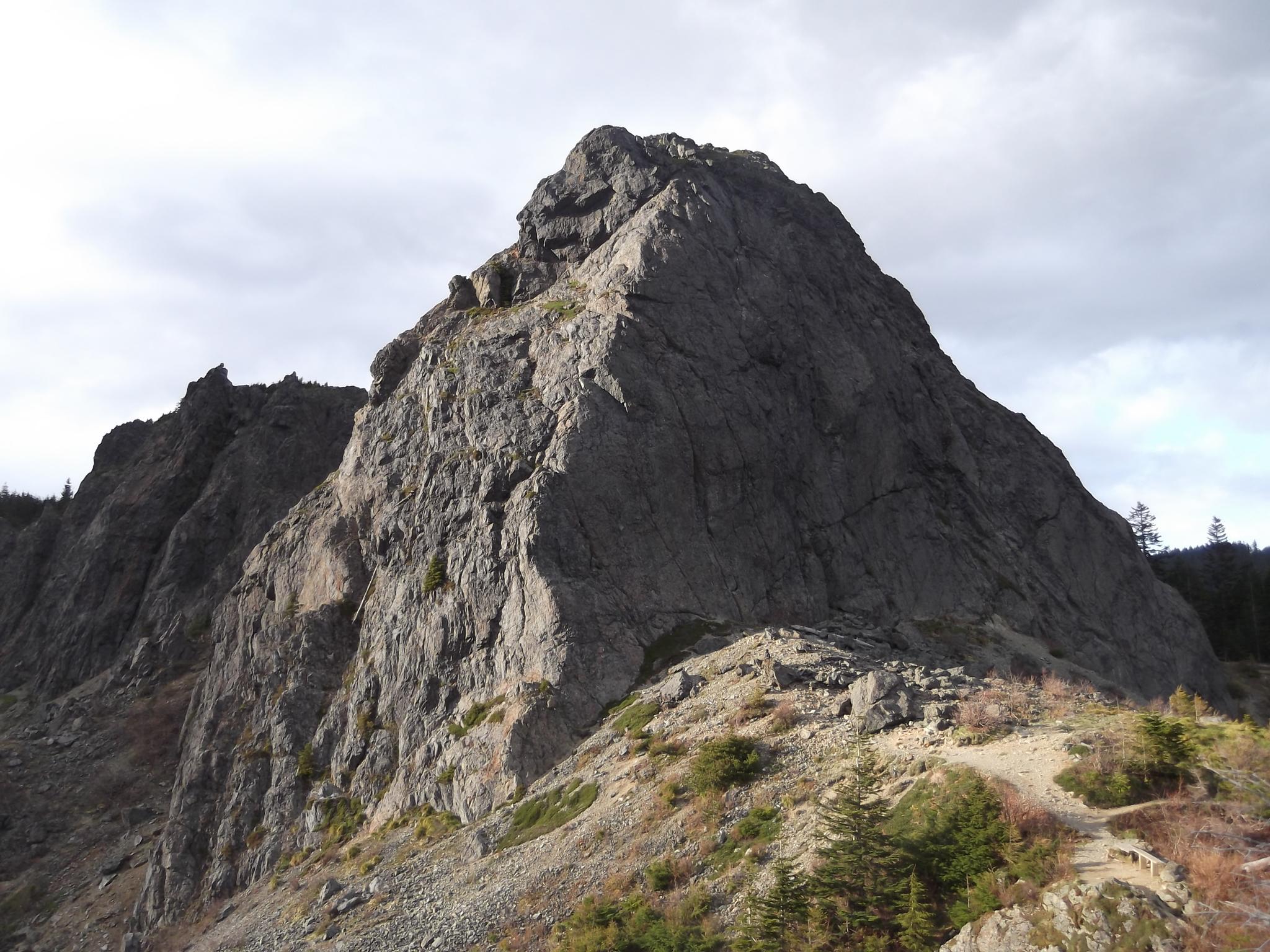 A large, rugged rocky mountain peak under an overcast sky.