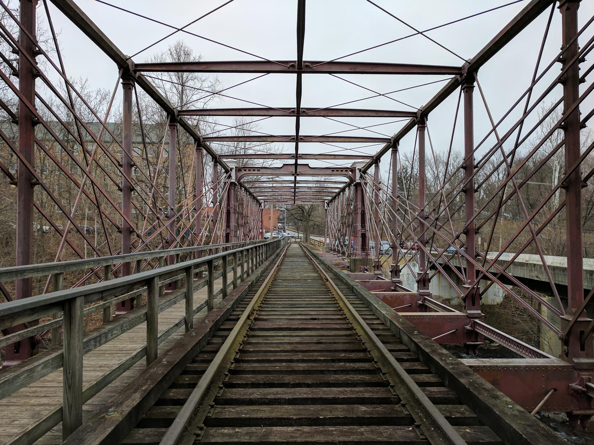 Long, old metal and wooden railroad bridge under an overcast sky.