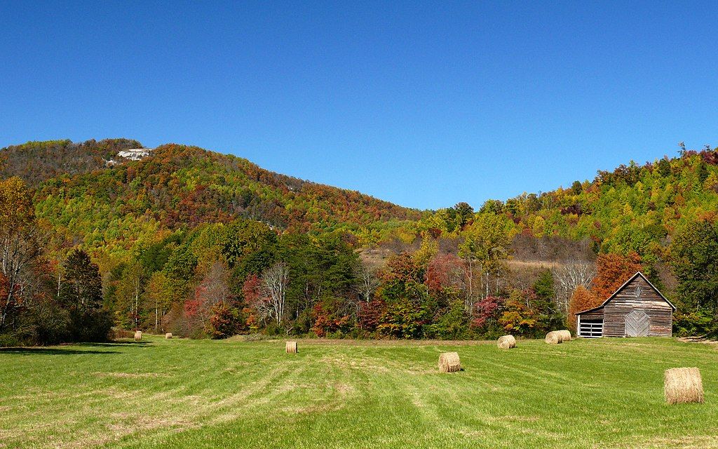 Rustic barn and hay bales in a sunny field with vibrant autumn mountains. - Lower Janita Lake – NC 2 – Mountains to Sea Route loop from Peters Creek Parkway Walmart Shelter