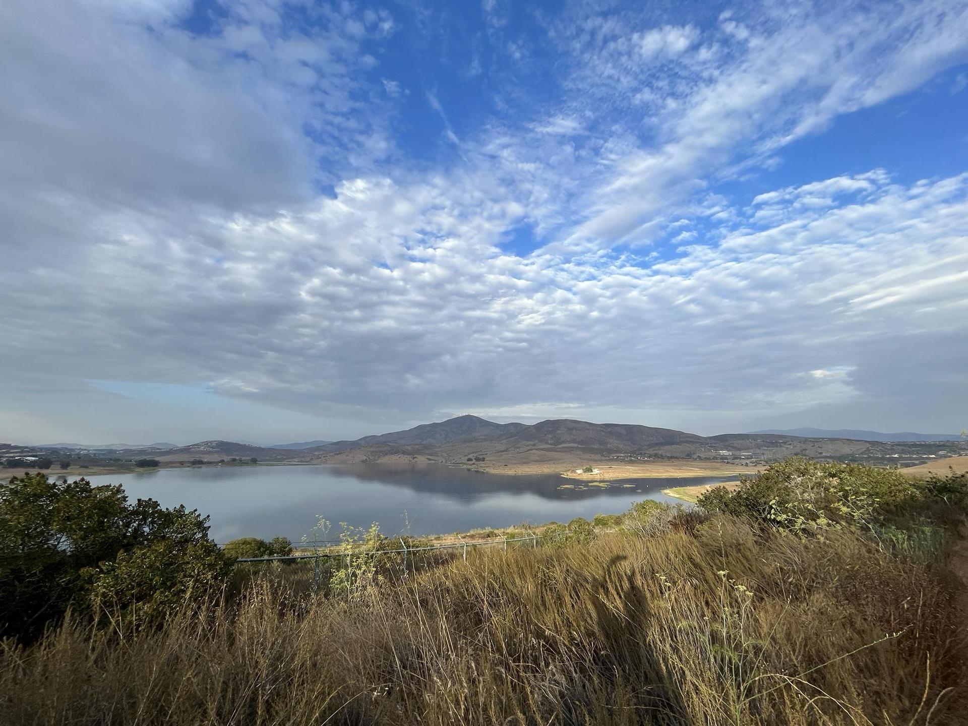 Expansive lake reflecting mountains under a partly cloudy blue sky.