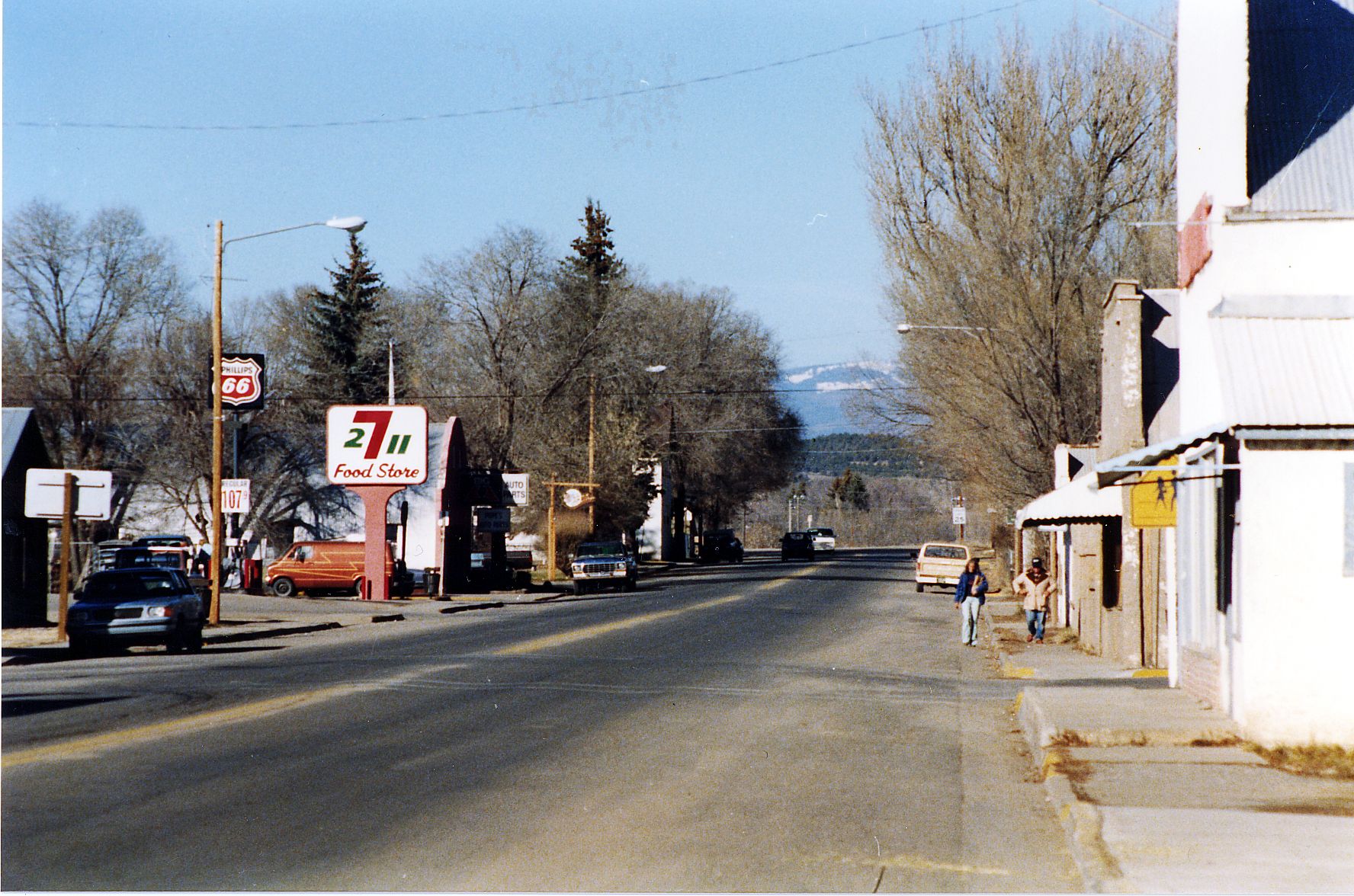 Sunny street with buildings, cars, people, and distant mountains. - Bayfield & Ignacio loop