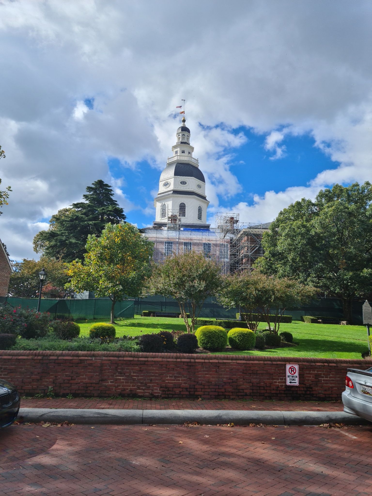 Grand domed building with scaffolding, surrounded by green trees and lawn. - Maryland State House – Annapolis City Dock loop from Annapolis