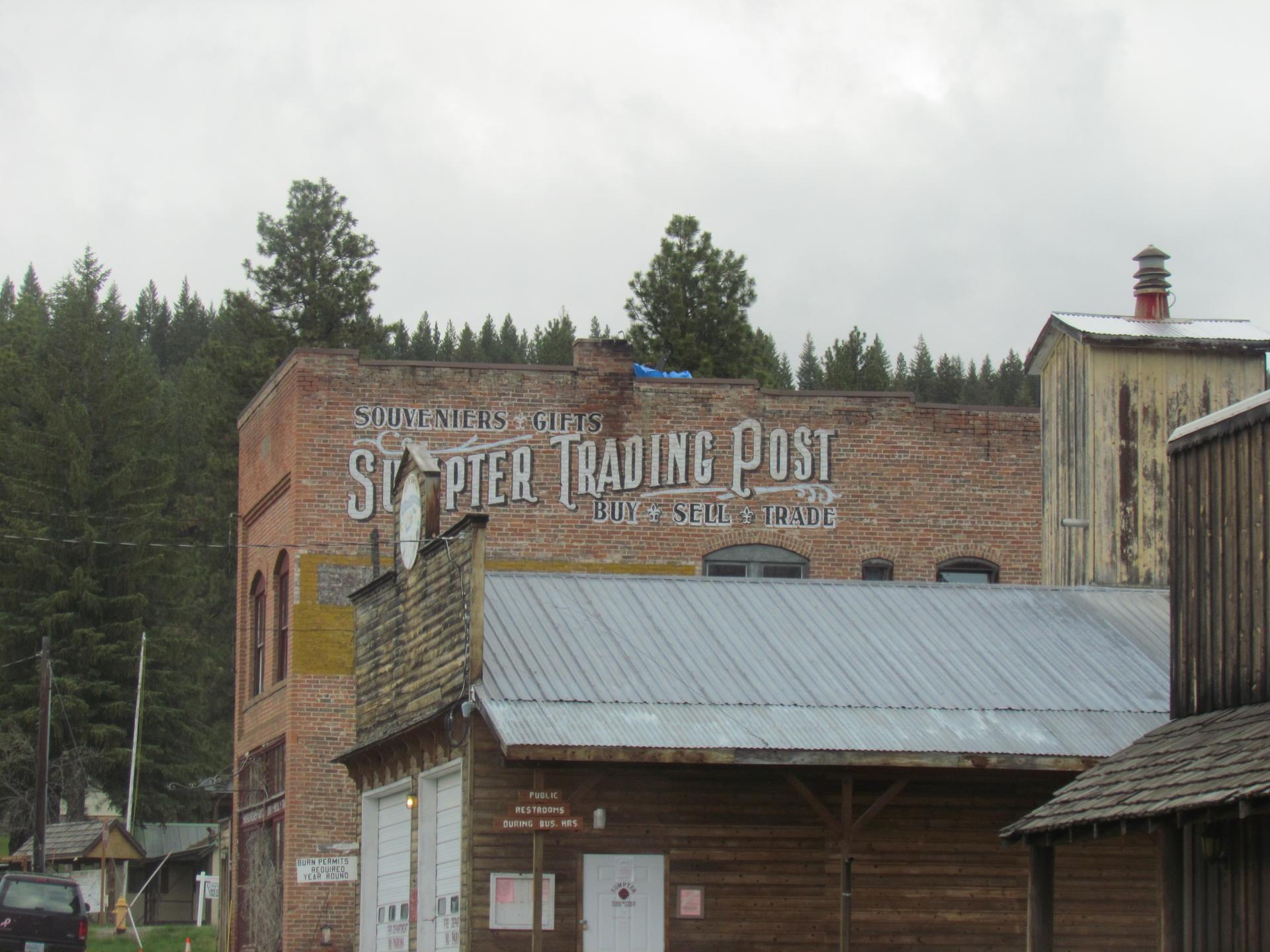Old brick trading post building with painted sign under an overcast sky.