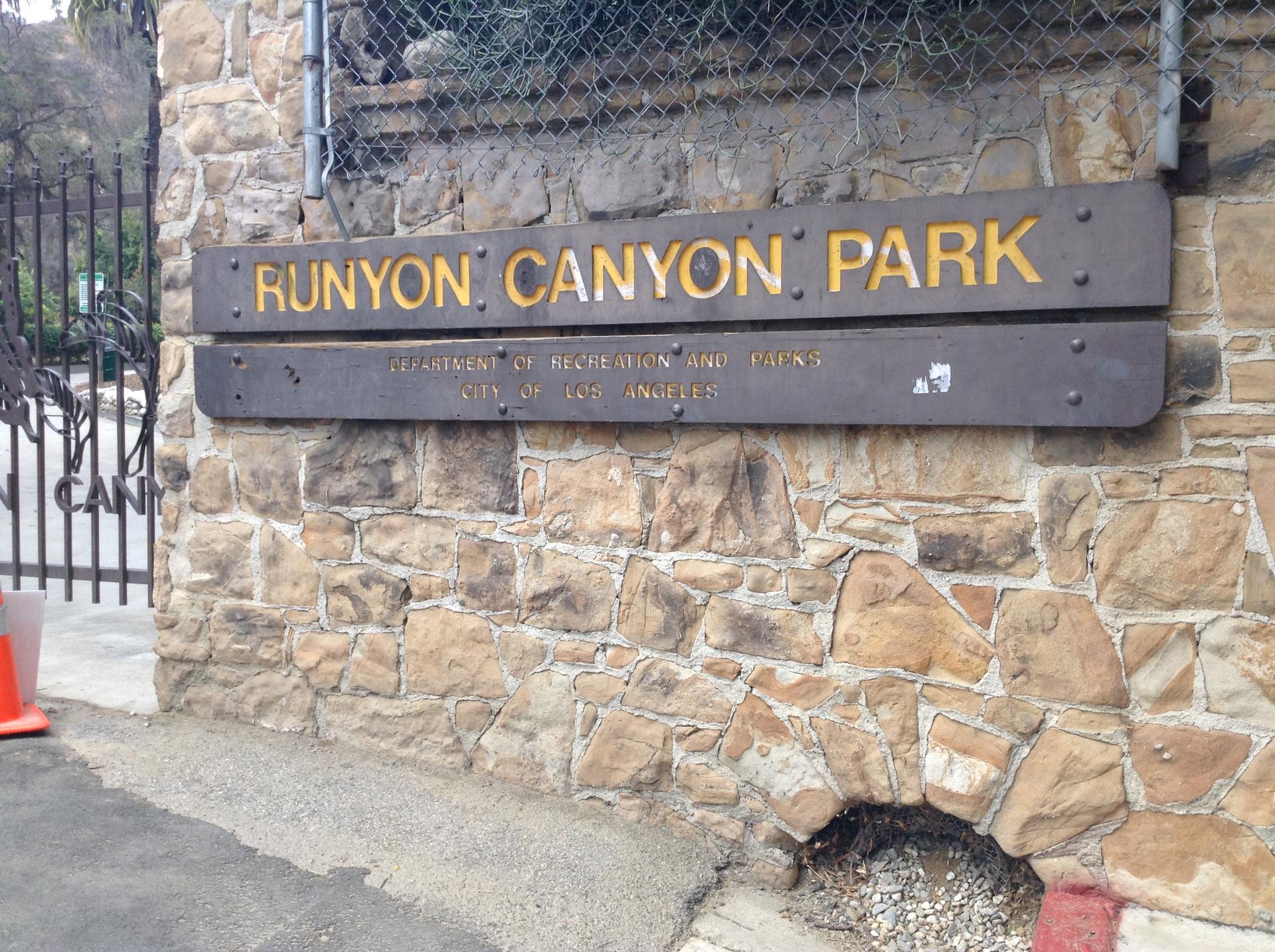 A stone wall with a wooden sign and a metal gate.