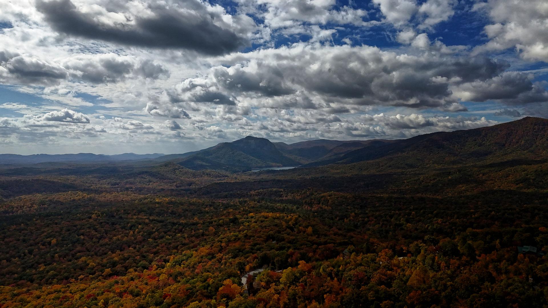 Expansive autumn mountain landscape under a dramatic cloudy sky.