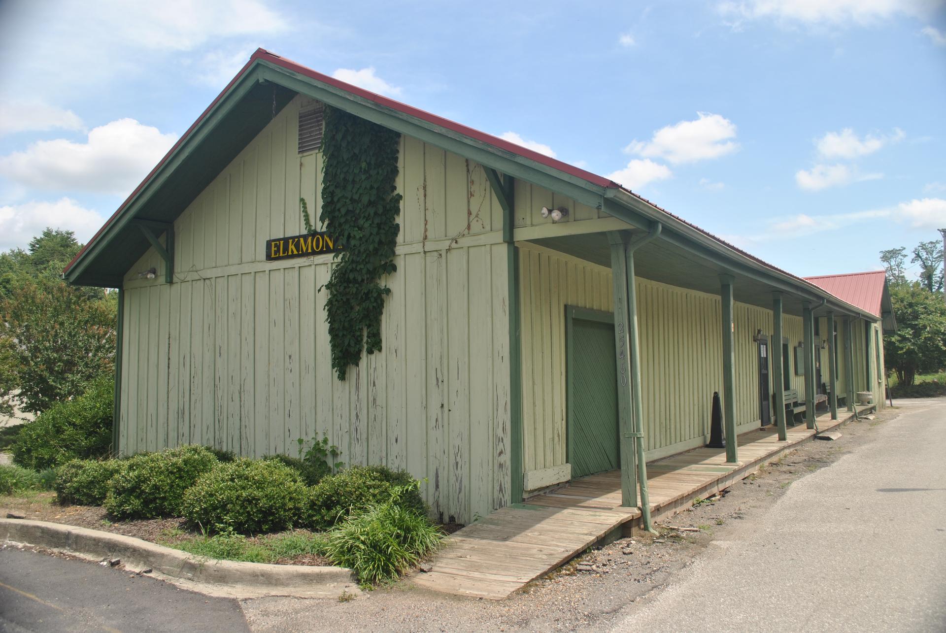 A light-colored wooden building with a red roof under a cloudy sky.