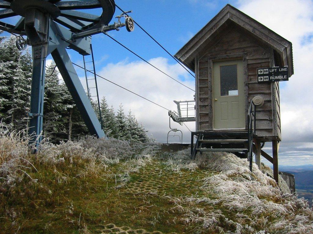Rustic wooden hut and ski lift on a frosty mountain top.