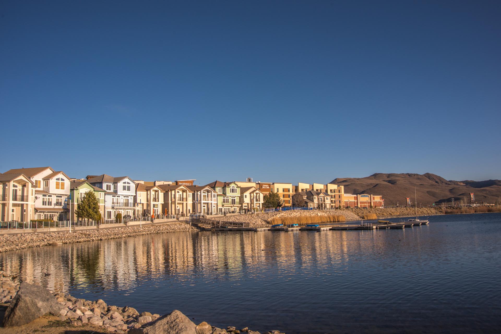 Waterfront houses and boats on a lake under a clear blue sky.