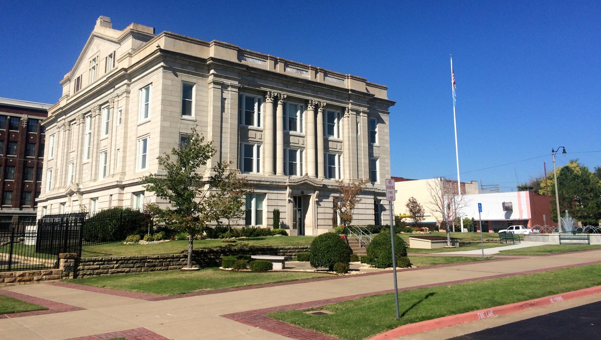 A grand, light-colored classical building with columns under a clear blue sky.