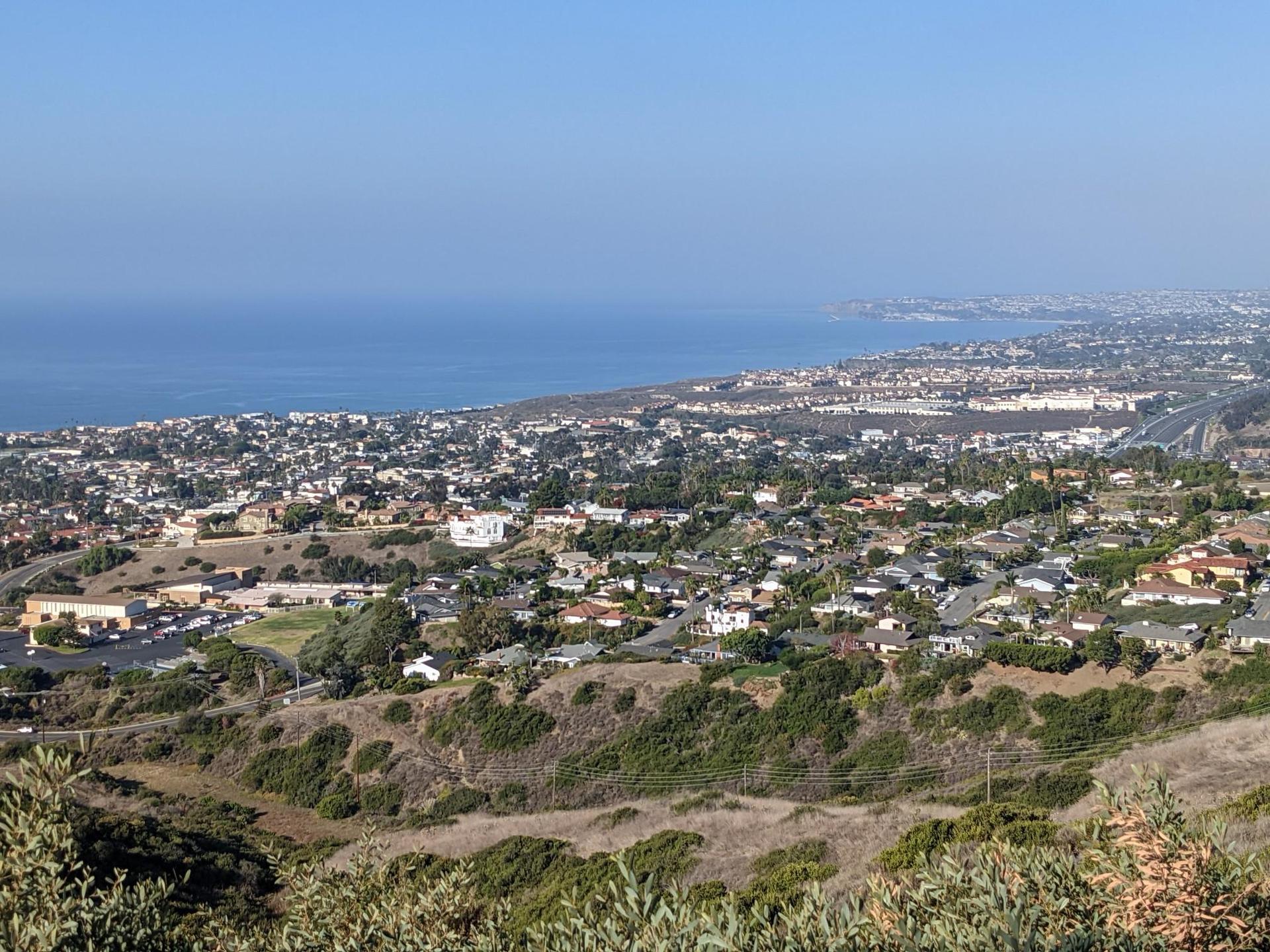 Expansive view of a coastal city and ocean under a clear blue sky.
