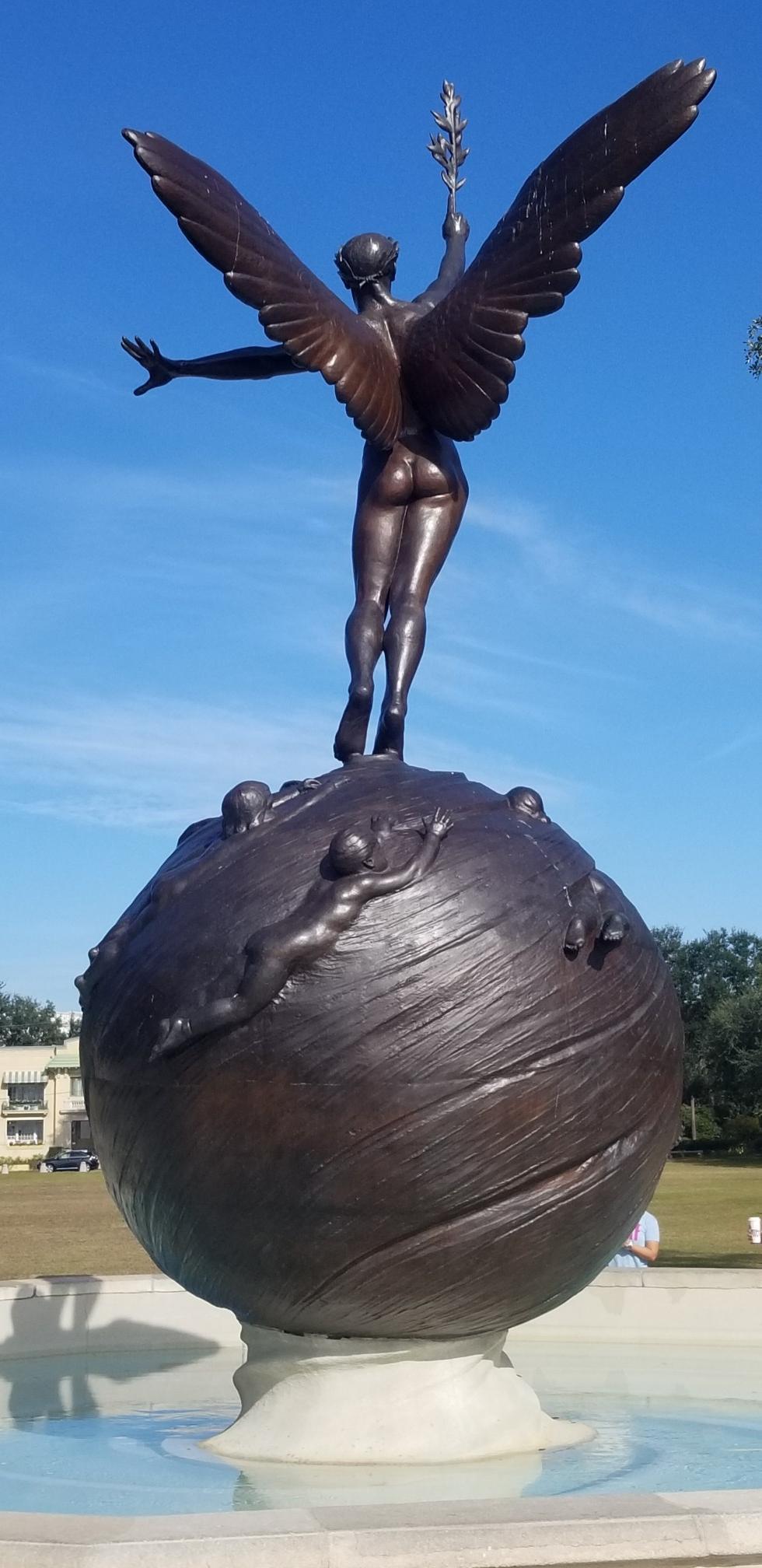 Bronze winged statue of a woman standing on a globe.