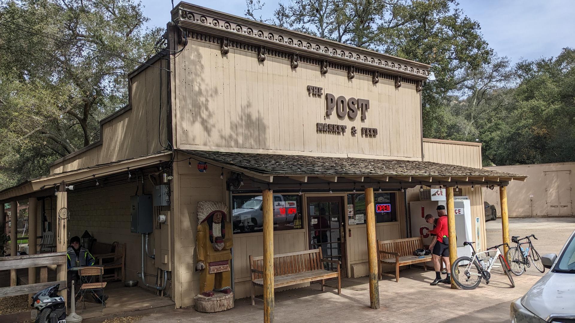 Old-fashioned general store building with a person and bicycles outside.