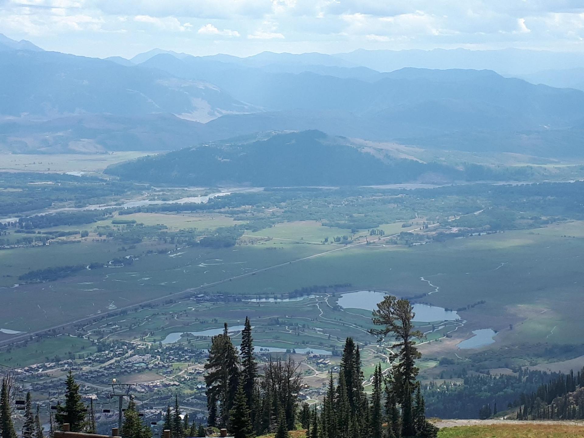 An expansive aerial view of a valley with lakes, rivers, and distant mountains.