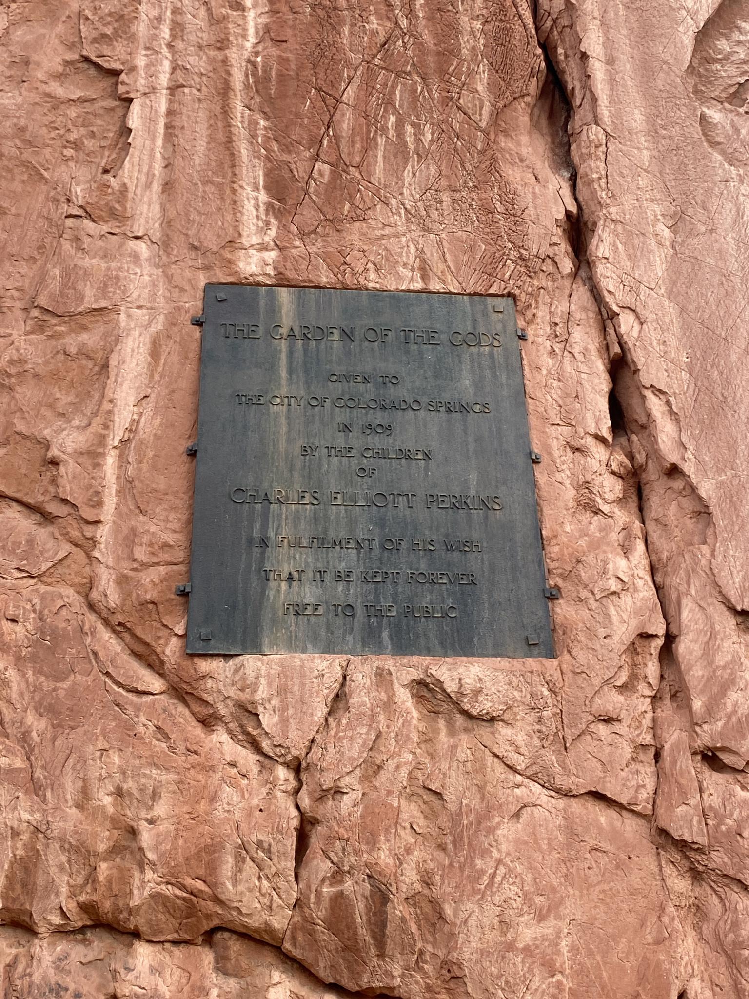 Close-up of a dark metal plaque mounted on a textured red rock.