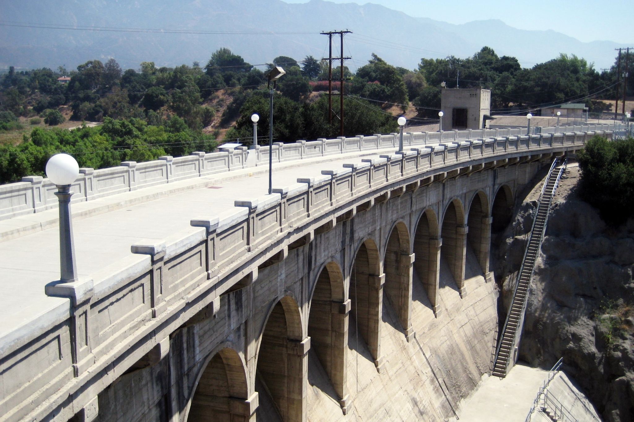 A large concrete arch bridge spans a valley under bright daylight. - Hahamongna Watershed South Loop