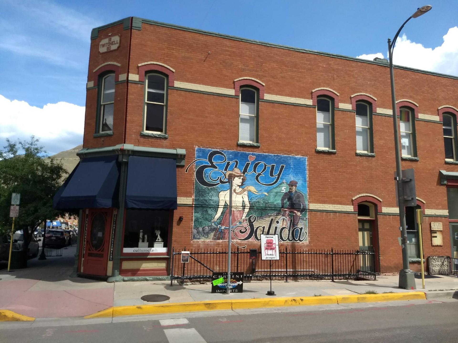 Brick building with a large colorful mural under a bright blue sky.