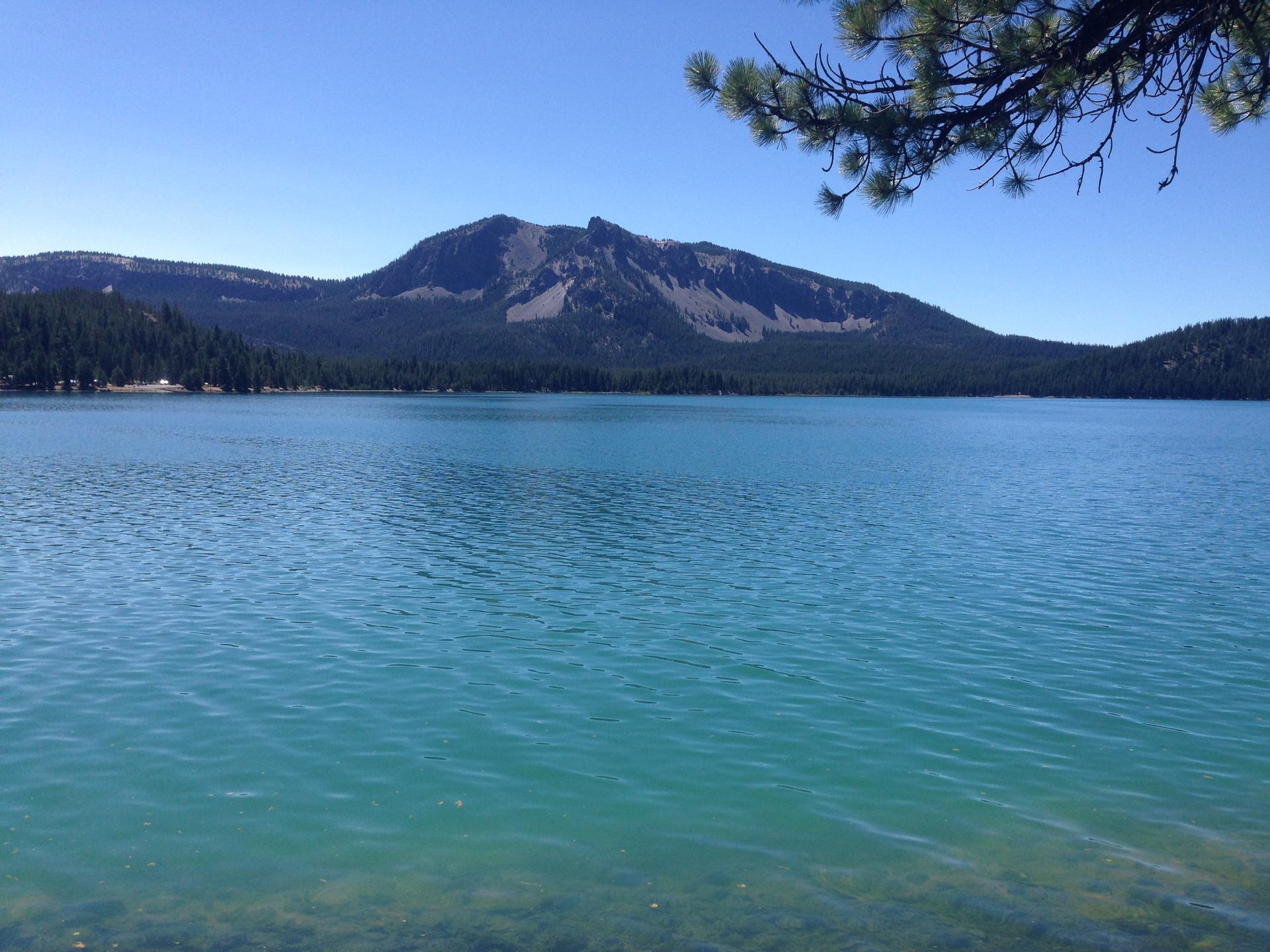 A vast blue lake reflects distant mountains under a clear sky.