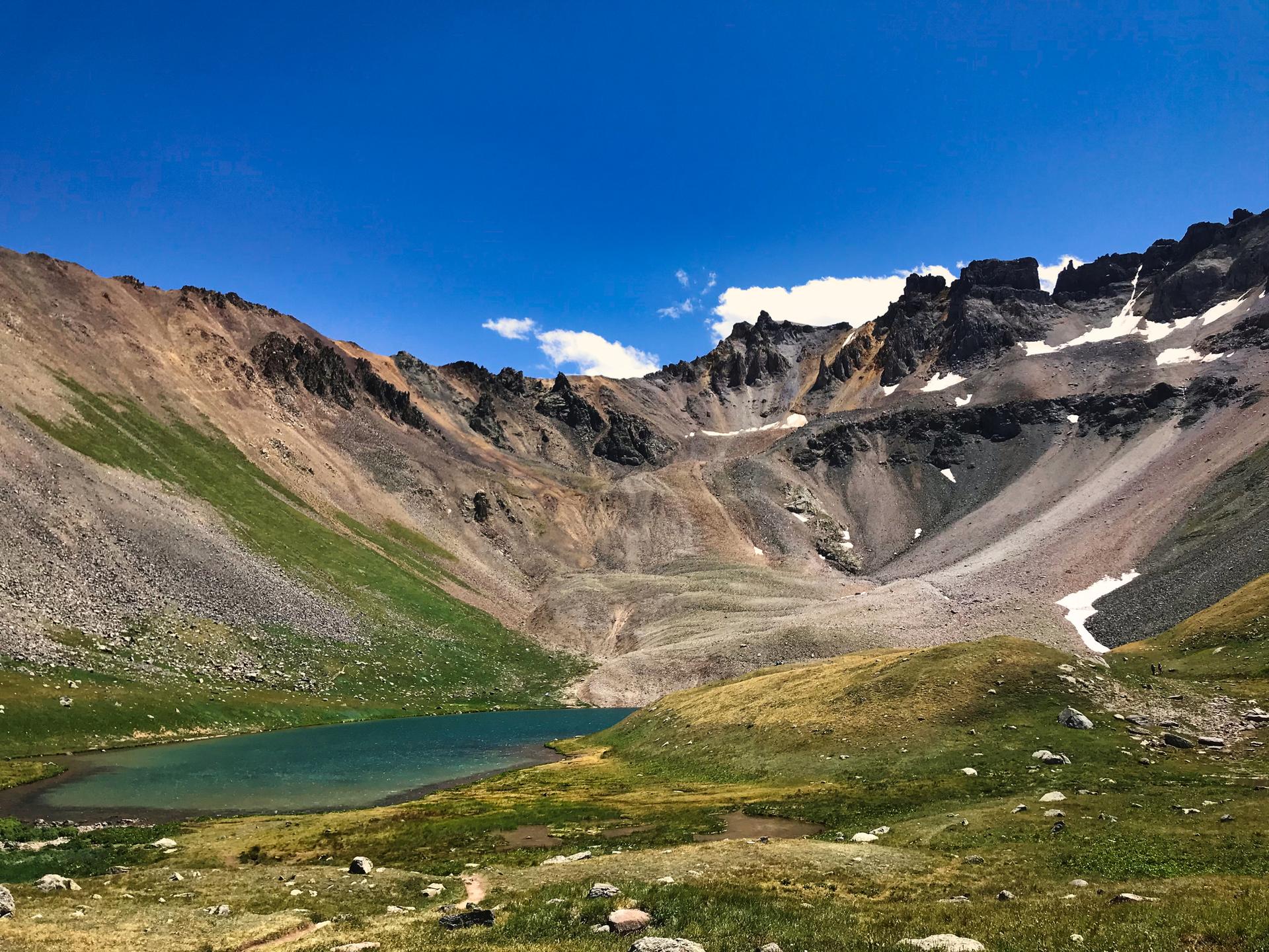 Vibrant blue alpine lake nestled among rugged, rocky mountains under a clear sky.